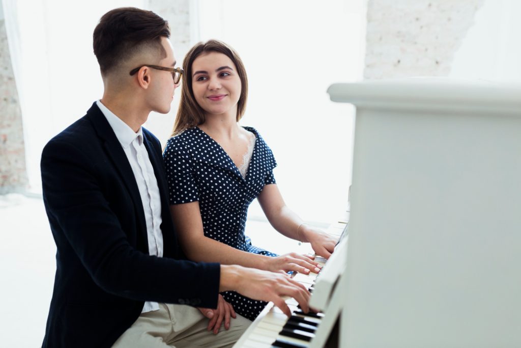 attraktives junges Paar spielt Klavier und schaut sich an